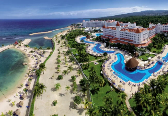 Victorian-style oceanfront resort architecture surrounded by palm trees at Bahia Principe Grand Jamaica in Runaway Bay.