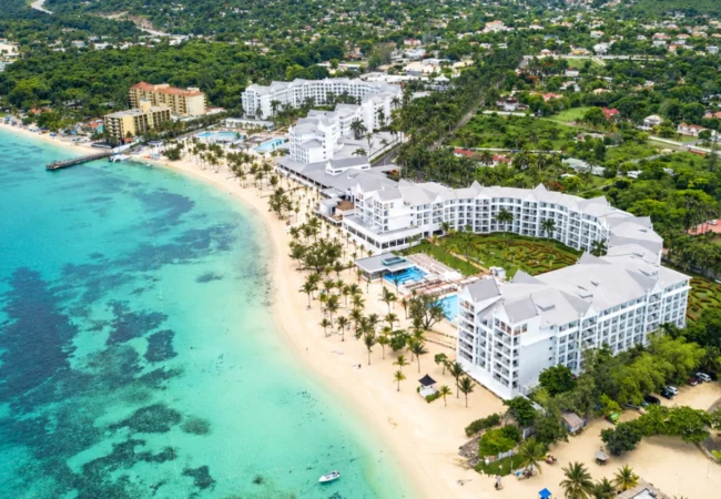 Grand oceanfront resort architecture and tropical palm trees along Mammee Bay at Hotel Riu Ocho Rios Jamaica.