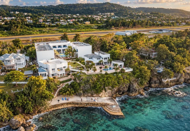 Cliffside luxury villa estate architecture surrounded by manicured tropical gardens and oceanfront scenery in Jamaica.